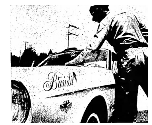 Period newspaper photo of a police officer approaching a car nicknamed 'Bandit'
